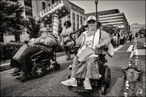Group of ADAPTers in wheelchairs marching down the street.