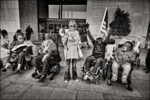 Group of ADAPTers holding signs and a megaphone outside of Health and Human Services