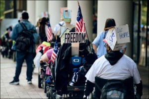 ADAPTer with sign saying “Freedom” in a line of other ADAPTers.